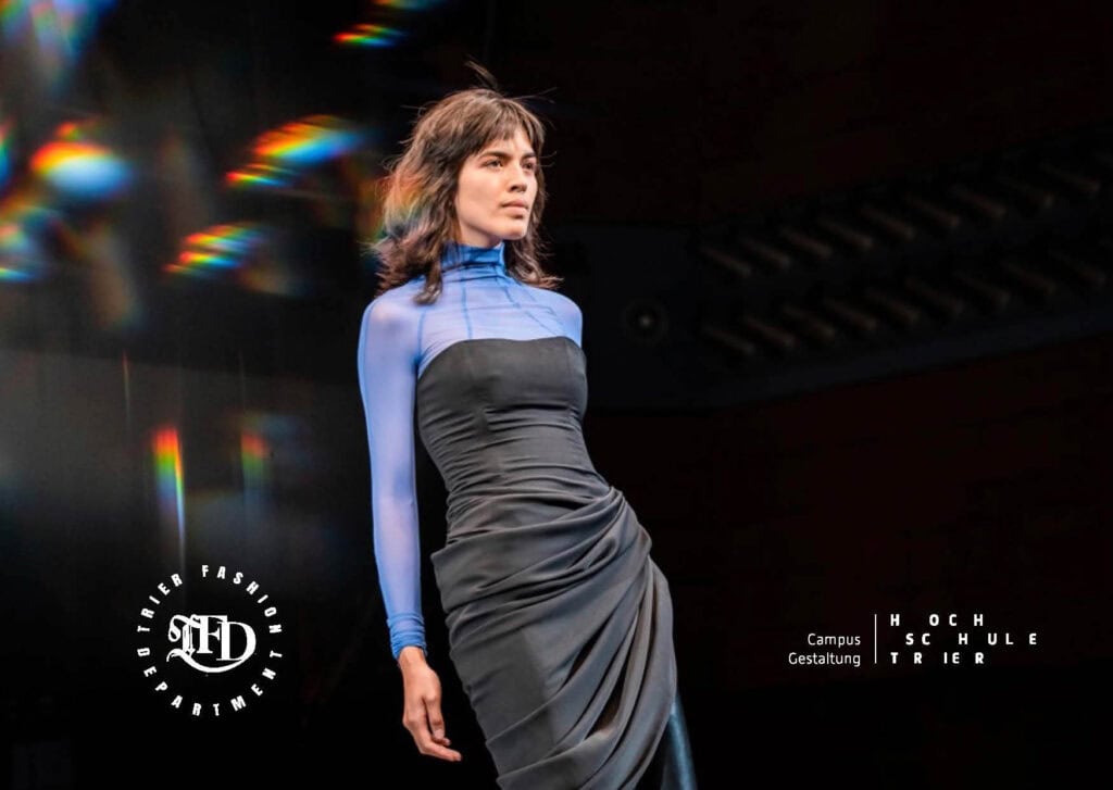 Model in eng anliegendem, schwarz-blauen Kleid mit Drapierungen